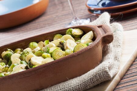 Roasted parsnips and brussel sprouts in terracotta baking dish の写真素材