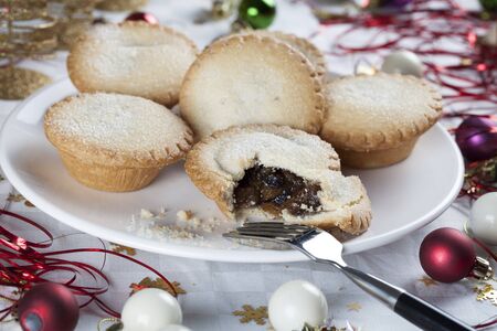 Mince pies on a plate surrounded by holiday decorations の写真素材