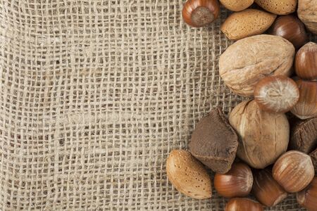 Whole unshelled hazelnuts, walnuts, amonds and brazilnuts  on burlap sack with copy spaceの写真素材