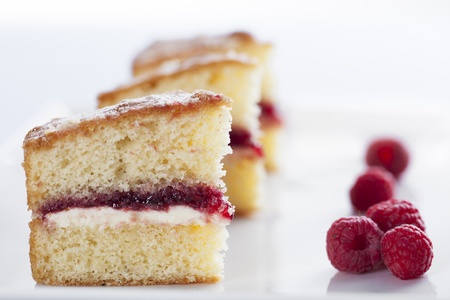 Victoria sponge cake with cream and jam filling, served with raspberriesの写真素材