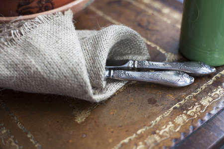 Cutlery wrapped in a burlap cloth on a vintage table の写真素材