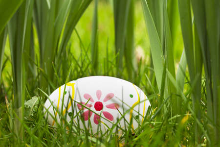 Painted Easter egg hidden in the grass and bulbs 