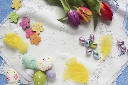 Easter goodies with chocolate eggs wrapped in foil, tulips and decorated eggs 