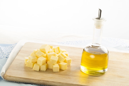 Olive oil in bottle and butter cubes on food preparation surface の写真素材