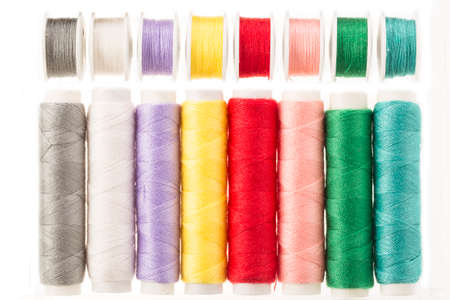 Colorful bobbins and spools of threads isolated on white