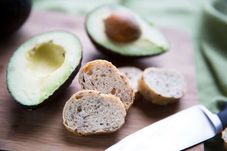 Fresh avocado cut in half and small slices of bread for making avocado toast.の写真素材