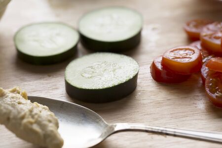 Getting ready to make healthy cucumber and hummus snacks topped with tomatoes.の写真素材