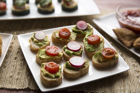 Healthy bites of avocado toast topped with tomato and radish slices.の写真素材