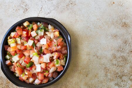 Bowl of fresh pico de gallo on stone surface with copy space and viewed from above.の写真素材