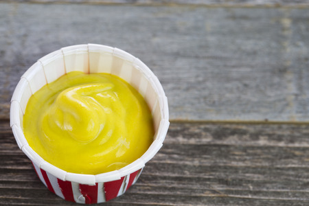 Mustard in a paper serving cup close up.の写真素材