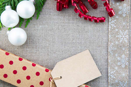 Gift box, ribbons and Christmas ornaments  on linen creating frame with copy space in center.の写真素材