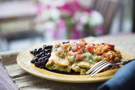 Vegetarian tamale dinner with black beans and rice topped with pico de gallo and salsa verde.