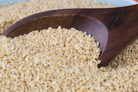 Wooden spoon full of bulgur wheat.の写真素材