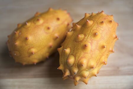 Two whole kiwano fruits on wooden surfaceの写真素材