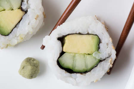 Vegan cucumber and avocado uramaki sushi rolls with wasabi and chop sticks.の写真素材