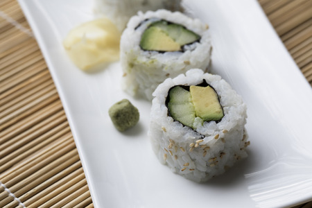 Vegan cucumber and avocado uramaki sushi rolls with wasabi and pickled ginger.の写真素材