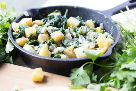Iron pan with cooked potatoes and spinach for breakfast or taco filling.の写真素材