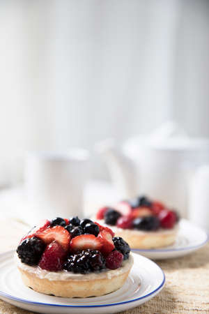 Two mixed berry tarts with tea kettle in backgroundの写真素材