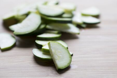 Thin slices of zucchini half on wooden cutting surfaceの写真素材