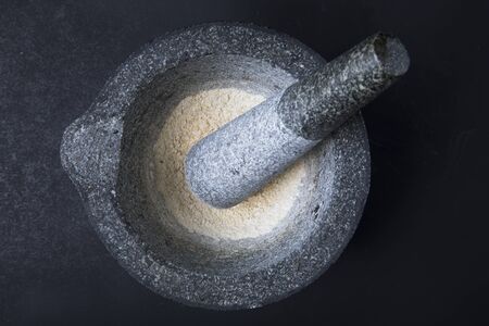Stone mortar and pestle with dried onion on dark surface.の写真素材