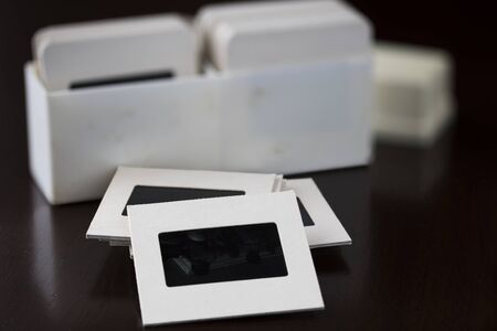 Old slide film transparencies in cardboard frames and container in backgroundの写真素材