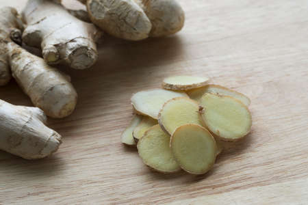 Ginger root and slices on cutting boardの写真素材