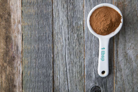 Ground cinnamon in a porcelain tablespoon on a wooden surface with copy space.の写真素材