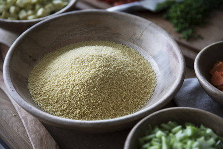 Polenta in wooden bowl on table with other ingredients.の写真素材
