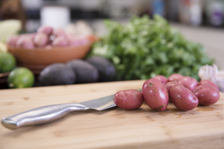 Small red potatoes on cutting board with knife in kitchenの写真素材