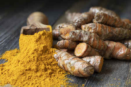 Scoop of turmeric powder and turmeric roots, landscape orientationの写真素材