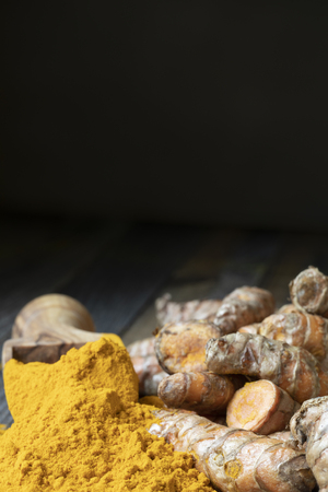 Scoop of turmeric powder and turmeric roots, vertical orientation with copy spaceの写真素材
