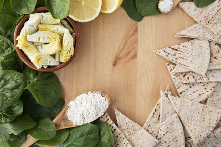 Artichoke hearts, spinach, lemon and other ingredients for vegan dip flat lay with copy space