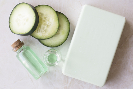 Cucumber extract in small bottle with bar of soap and cucumber slices flat layの写真素材