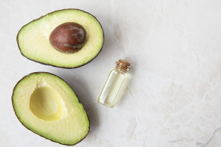 Small bottle of avocado oil and avocados on marble surfaceの写真素材