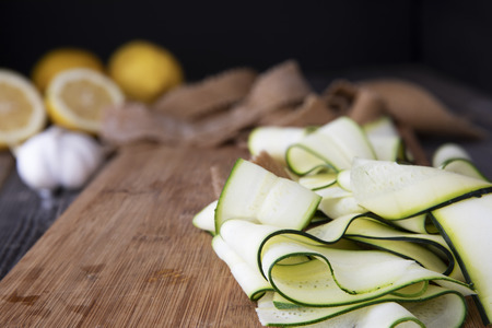 Fresh zucchini sliced into ribbons and sitting on wooden cutting board.の写真素材
