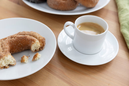 Cup of Espresso and Partialy Eaten Donut on a Breakfast Tableの写真素材