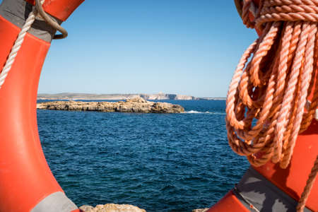 Life Ring with Comino tower View. framed in the orange life ring. at xatt l ahmar Gozo Malta.の写真素材