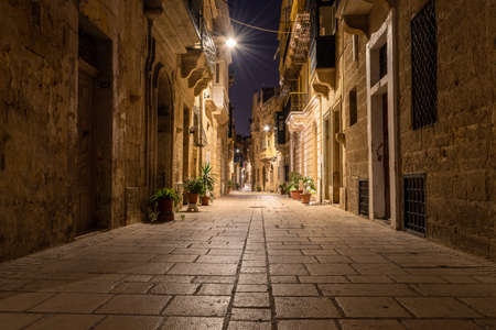 Street in Birgu at Night, long exposure shot. low angle. people motion blurred. nobody there, peaceful roads by night. Malta narrow streets.の写真素材