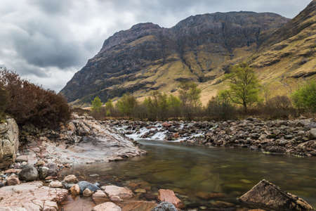 Glencoe river with smooth water flow and cloudy day. hill views at the backの写真素材