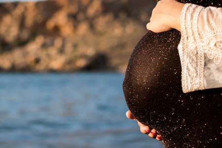 A beautiful pregnant woman on the beach touching her belly with love and care copy spaceの写真素材