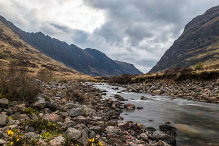 Glencoe river with smooth water flow and cloudy day. hill views at the backの写真素材