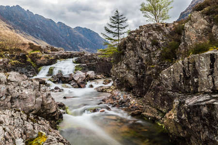 Glencoe river with smooth water flow and cloudy day. hill views at the back Rural scene