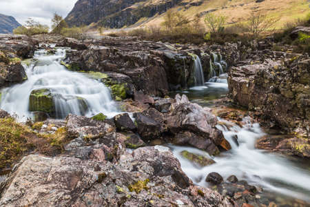 Glencoe river with smooth water flow and cloudy day. hill views at the backの写真素材