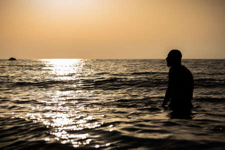 Mascular man relaxed in the water during sunset with nobody swimming around silhouette. side view horizontalのeditorial素材