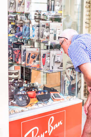 22nd SEP 2016 Valletta Malta. 60-70 years Old Man with two glasses on his head looking at a shop of sunglasses ray ban.のeditorial素材