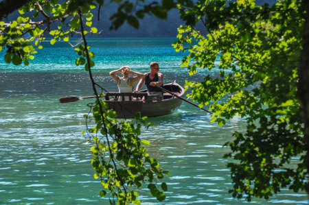 Young man sitting in a boat on the turquoise water of the Bled Lake, Sloveniaの写真素材