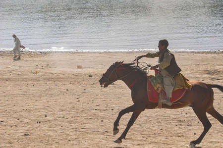 A man riding a horse on the beach in Jaisalmer, Rajasthan, India.の写真素材