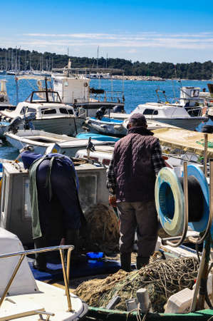 A fisherman with his fishing nets and boats in the port of the small town of Rovinj, Croatiaの写真素材