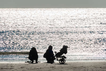 silhouette of family with baby child on Empty Beach in Grado on a sunny Winterday, Backlight...