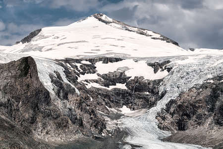 Mountain landscape with snow-capped peaks in the clouds.の写真素材
